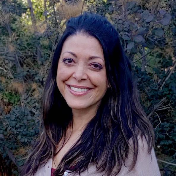 A portrait photo of Stacy Dicker outside with greenery behind her.