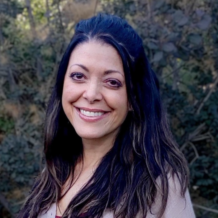 A portrait photo of Stacy Dicker outside with greenery behind her.