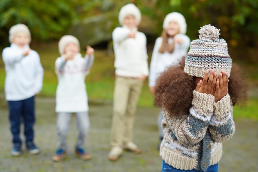 African-american girl expressing deep upset while several kids bullying her
