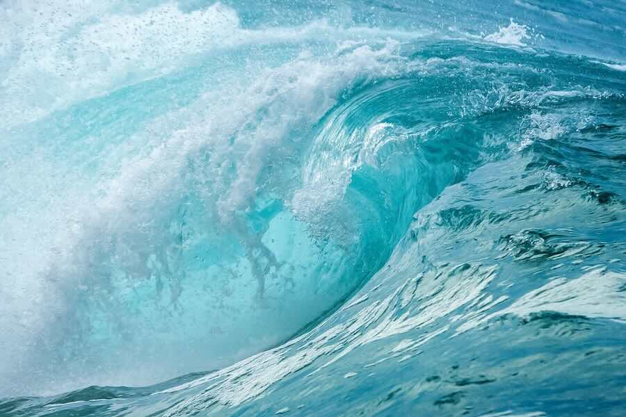 A large wave of blue water creating a tunnel or pipeling.